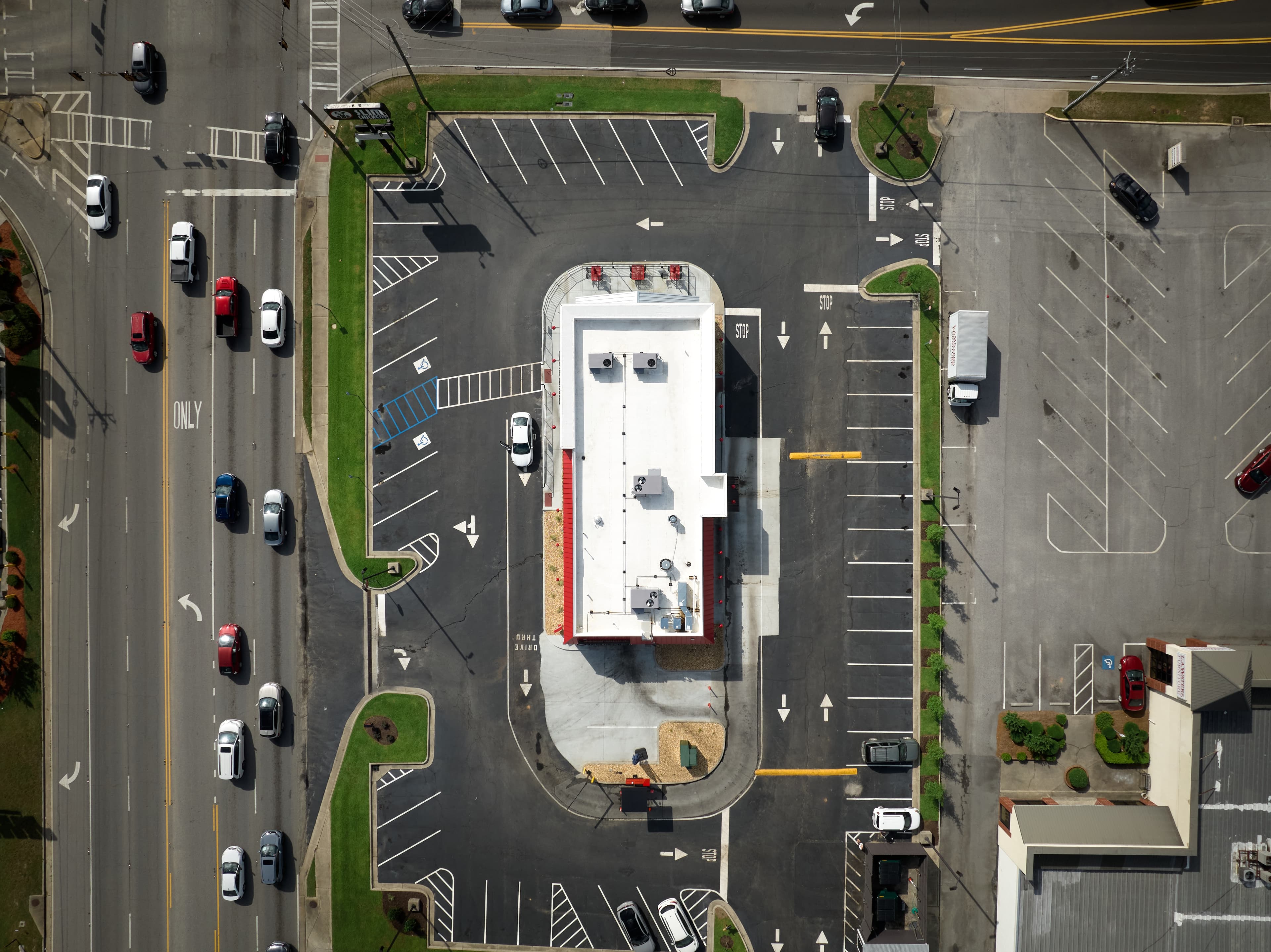 Wide-angle aerial image of Slim Chickens restaurant's newly-installed commericial roof. HVAC units are also present on the roof. The restaurant is surrounded by parking lot and roads.